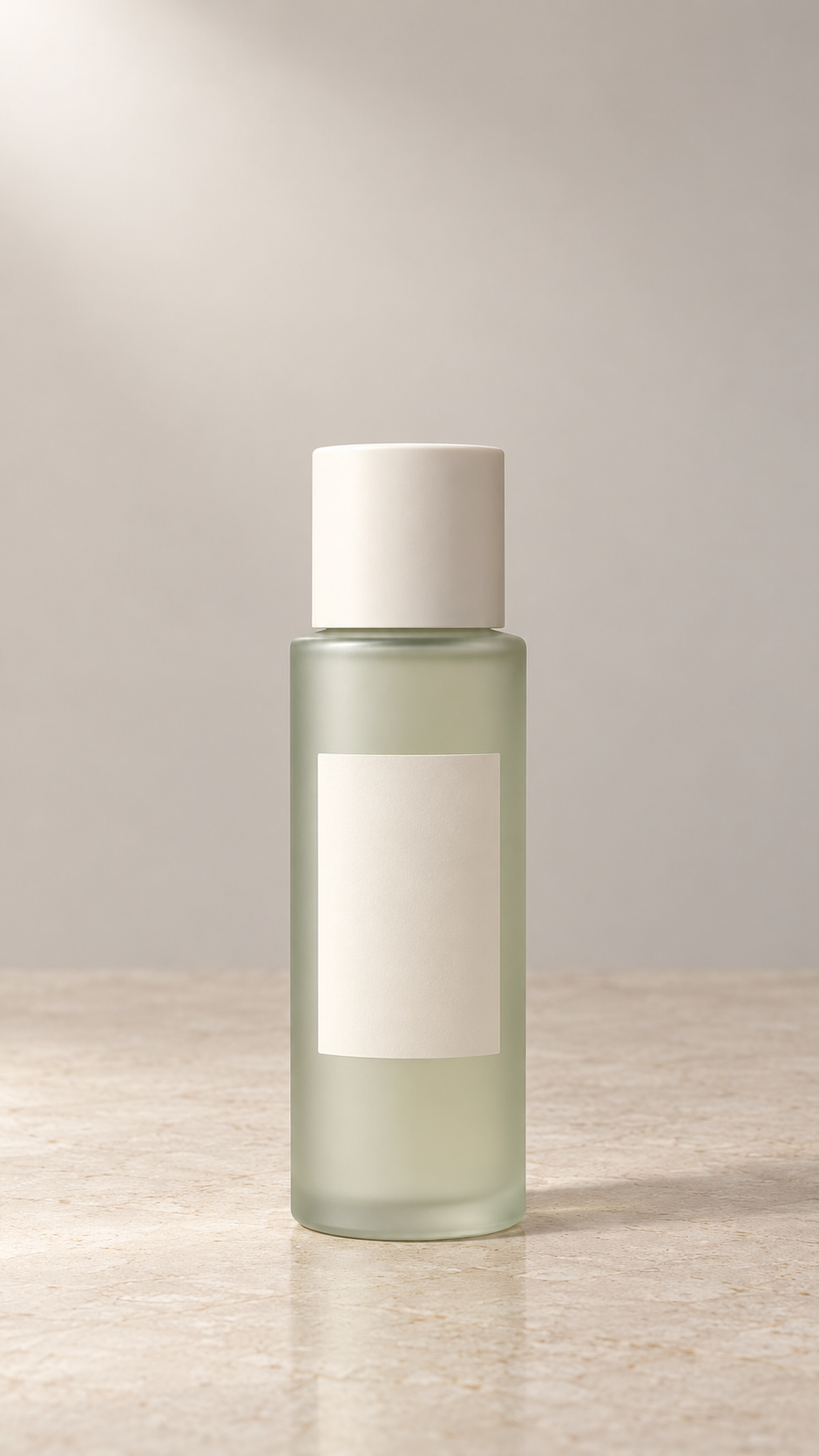 Illustrative packshot of a pale sage frosted skincare bottle with an ivory cap and blank label on a light stone tabletop.